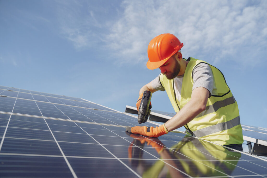 Man in a protective helmet. Installing stand-alone solar panel system after homeowners discovered the cost of solar