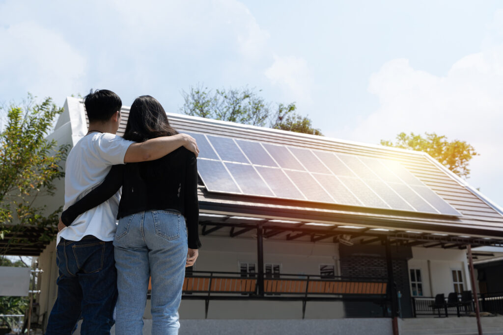 A couple stands looking at their roof after hiring a solar company to install solar panels on their home